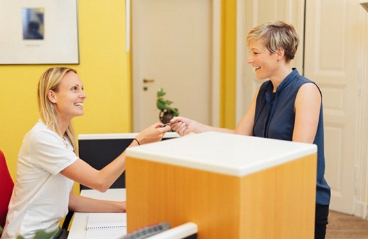 A patient handing her credit card to a dental employee.