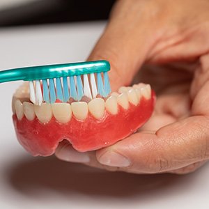 person cleaning dentures