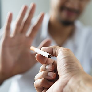 Man holding hand out to refuse cigarette being offered