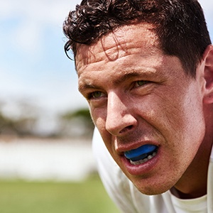 Man outside sweating with blue mouthguard over upper arch